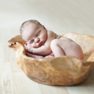 Newborn in big wooden bowl