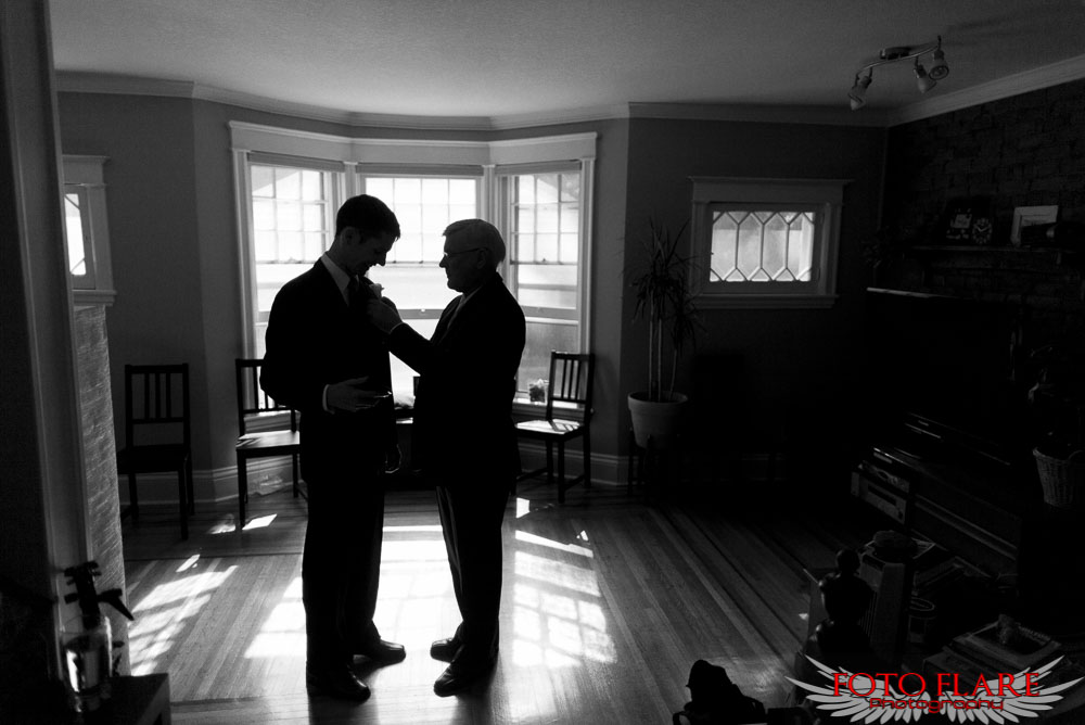 Grooms father helping with boutonnière