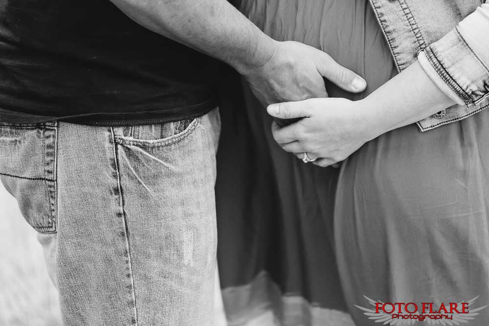 B&W photograph of dad holding onto the baby bump
