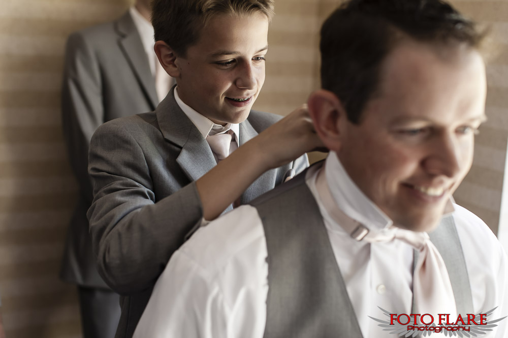 Grooms son helping with tie