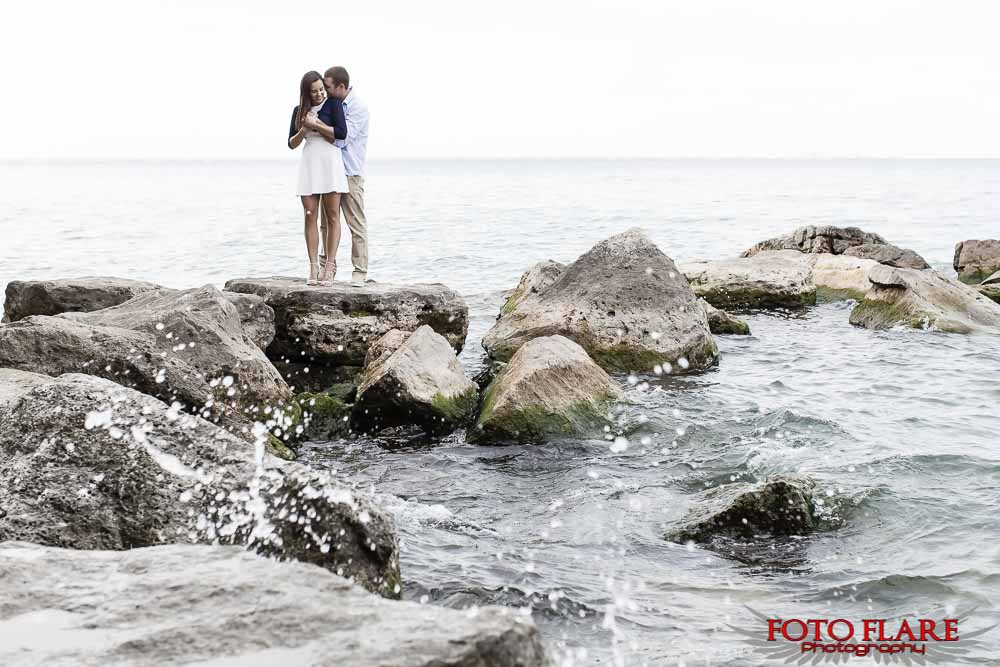 Couple standing on big boulders at the water