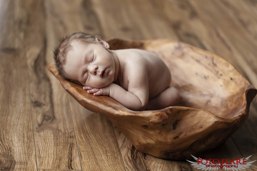 Baby in a wooden bowl sleeping