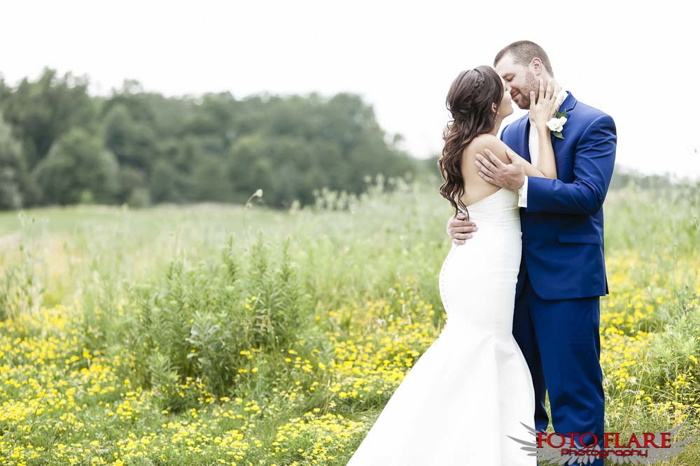 Bridal couple kissing in field