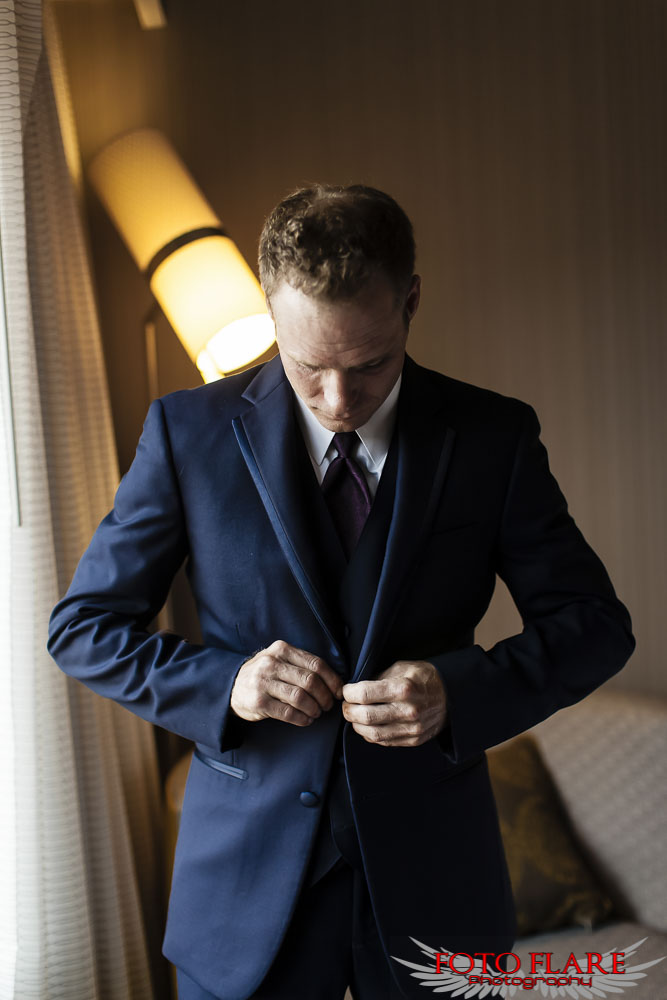 Groom buttoning his suit 